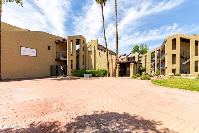 view of property featuring curved driveway and central AC unit
