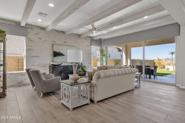 living room with ceiling fan, brick wall, light hardwood / wood-style flooring, and beam ceiling