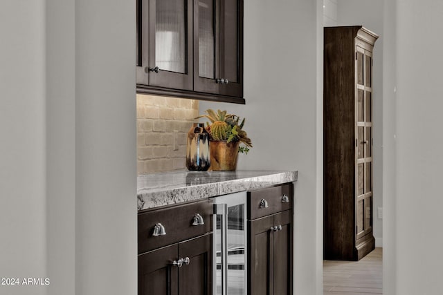 interior space with beverage cooler, dark brown cabinetry, light hardwood / wood-style flooring, and tasteful backsplash