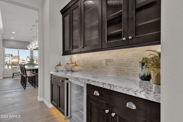 bar featuring light hardwood / wood-style floors, wine cooler, dark brown cabinetry, and light stone countertops