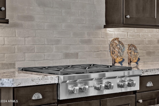 room details featuring light stone countertops, backsplash, dark brown cabinetry, and stainless steel gas cooktop