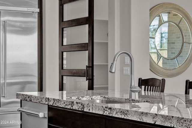 room details with light stone counters, sink, and stainless steel built in refrigerator