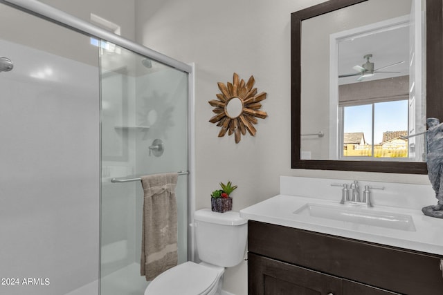 bathroom with toilet, vanity, ceiling fan, and a shower with shower door