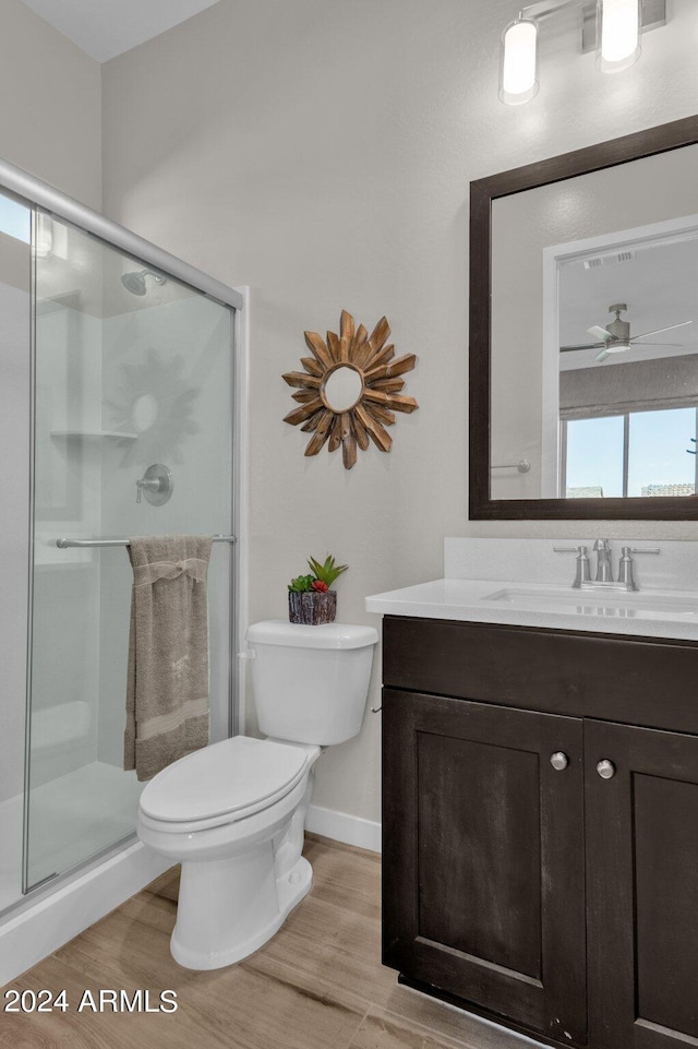 bathroom featuring toilet, vanity, ceiling fan, hardwood / wood-style floors, and a shower with shower door