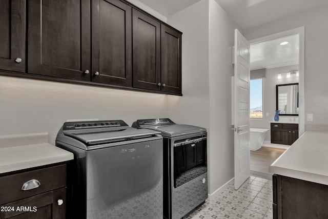 clothes washing area with cabinets and washer and clothes dryer