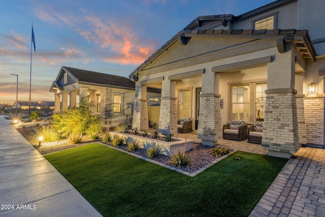 back house at dusk featuring a lawn