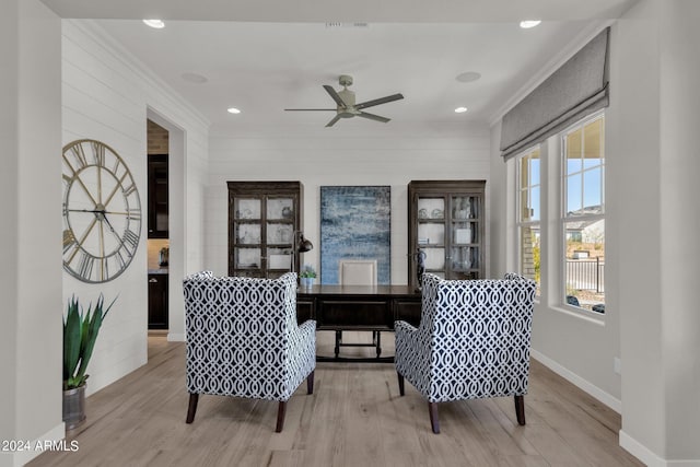 sitting room with light wood-type flooring, ceiling fan, and ornamental molding