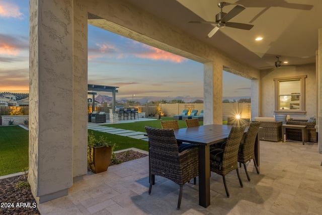 patio terrace at dusk featuring ceiling fan and an outdoor living space