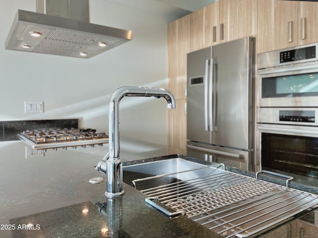 kitchen featuring range hood, light brown cabinets, dark stone counters, stainless steel appliances, and modern cabinets