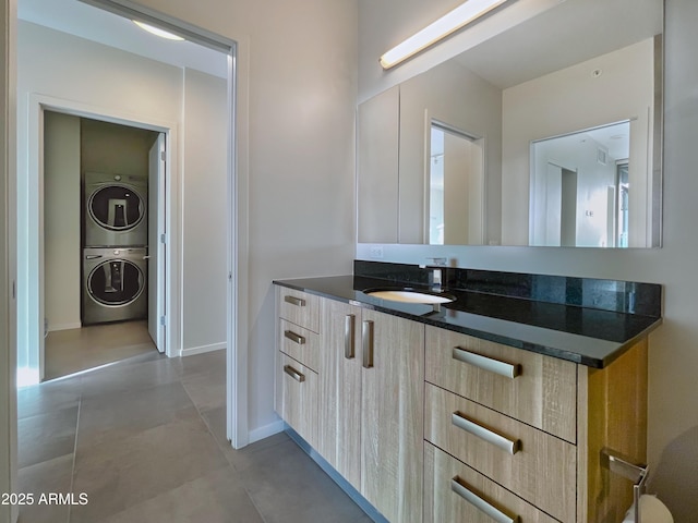 bathroom with baseboards, vanity, and stacked washer / dryer