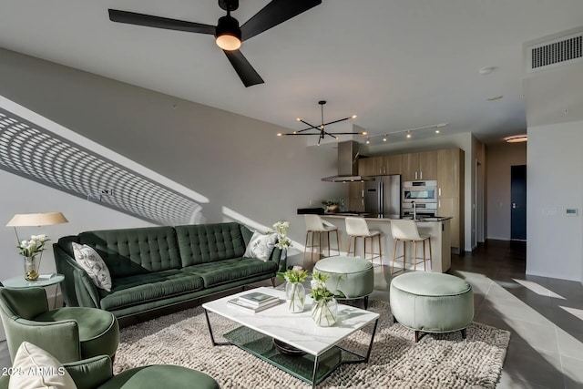 living area featuring ceiling fan with notable chandelier, dark tile patterned flooring, baseboards, and visible vents