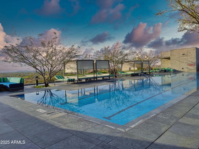 pool at dusk with a patio and a community pool