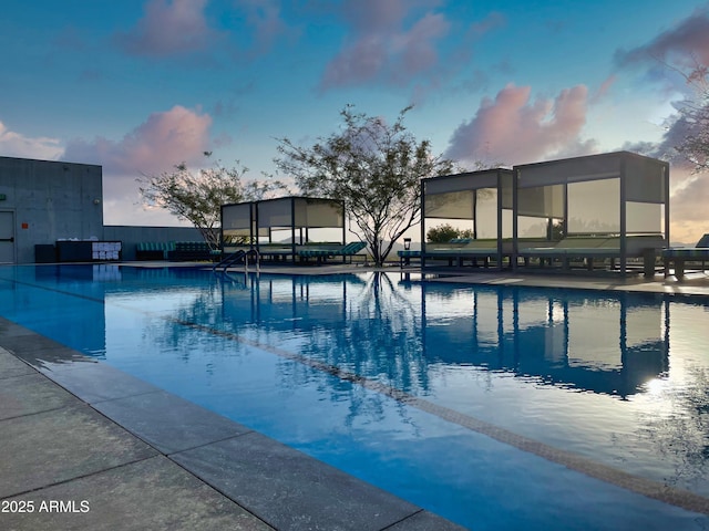 pool at dusk with a community pool and fence