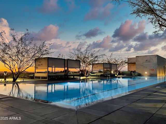 pool at dusk with a community pool and a patio area