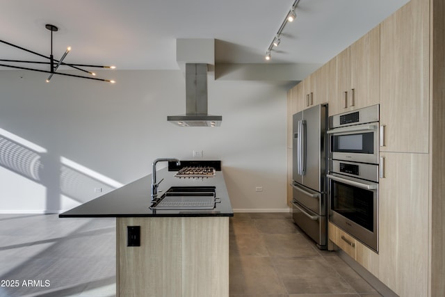 kitchen with modern cabinets, light brown cabinets, appliances with stainless steel finishes, a peninsula, and wall chimney range hood