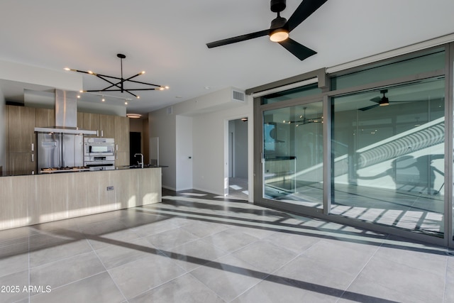 interior space with dark countertops, modern cabinets, island range hood, and ceiling fan with notable chandelier