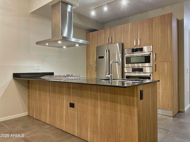 kitchen featuring a peninsula, baseboards, appliances with stainless steel finishes, and island range hood