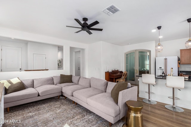 living room with ceiling fan, arched walkways, wood finished floors, and visible vents