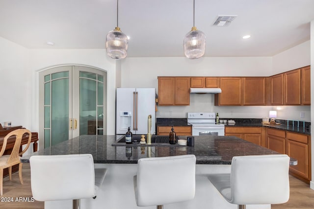 kitchen with french doors, visible vents, white appliances, brown cabinetry, and under cabinet range hood