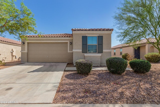 mediterranean / spanish house with an attached garage, a tile roof, concrete driveway, and stucco siding