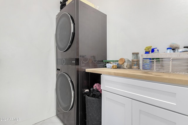 laundry area with stacked washer and dryer and baseboards