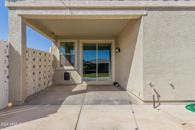 entrance to property featuring a patio area, stucco siding, and fence