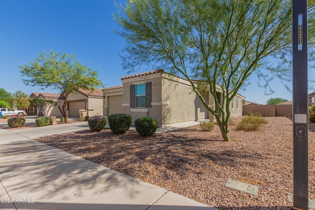 view of front of house with fence, a tiled roof, concrete driveway, an attached garage, and stucco siding