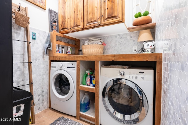 laundry area with light wood finished floors, cabinet space, and washer and dryer