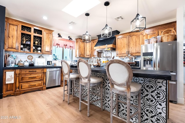 kitchen with stainless steel appliances, tasteful backsplash, visible vents, custom range hood, and light wood-style floors