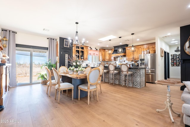 dining room with light wood-type flooring, recessed lighting, and an inviting chandelier