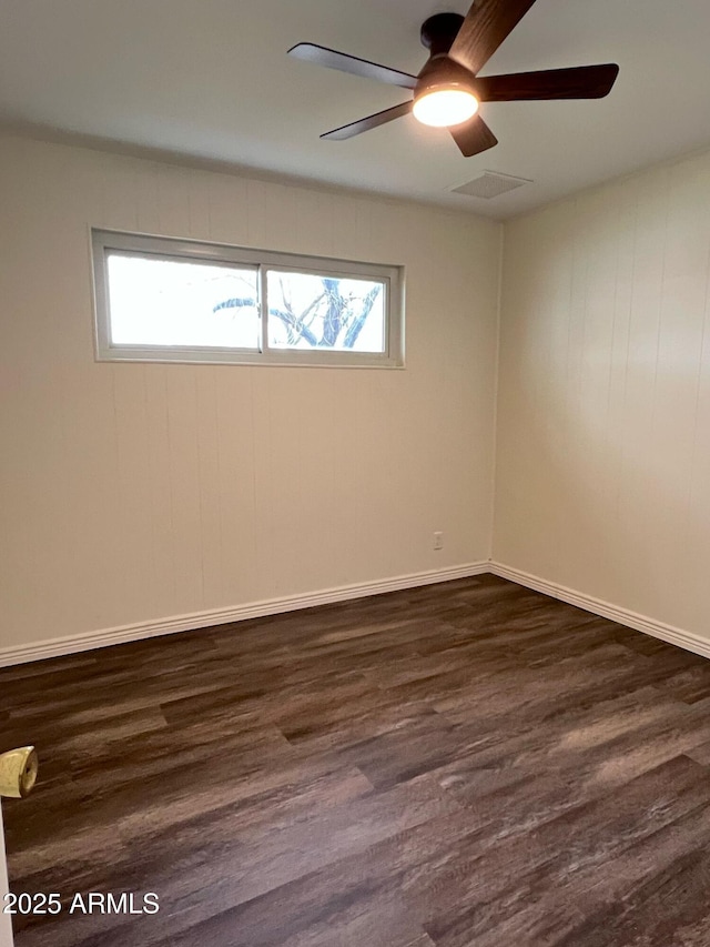 empty room featuring ceiling fan, a wealth of natural light, dark wood-type flooring, and visible vents