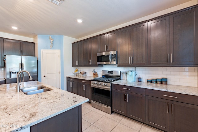 kitchen with sink, light stone counters, stainless steel appliances, and dark brown cabinets