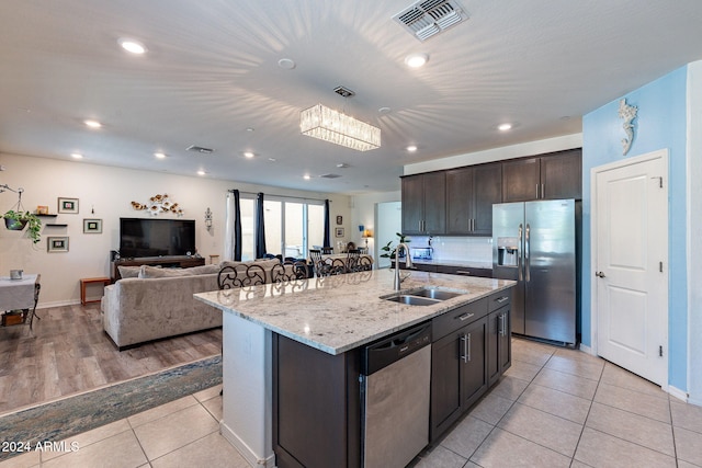 kitchen featuring stainless steel appliances, dark brown cabinets, sink, and a center island with sink