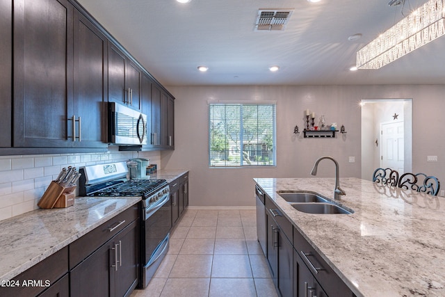 kitchen featuring stainless steel appliances, backsplash, sink, dark brown cabinetry, and light stone counters