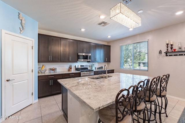 kitchen with appliances with stainless steel finishes, sink, decorative light fixtures, a breakfast bar, and a center island with sink