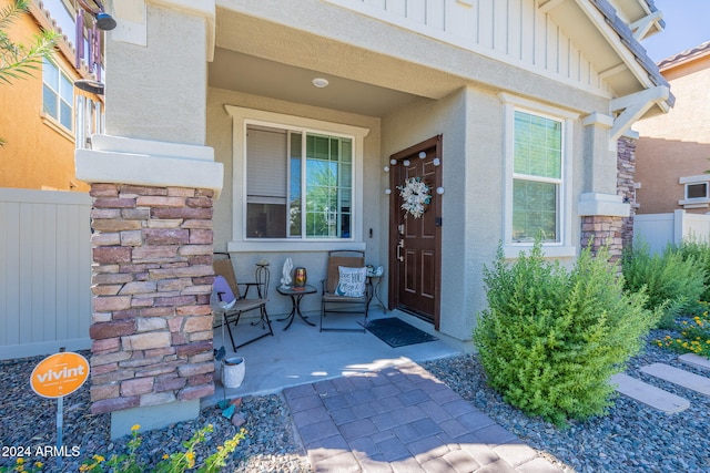 property entrance with fence, board and batten siding, stucco siding, and stone siding