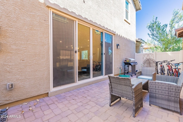 view of patio with an outdoor living space, fence, and a grill