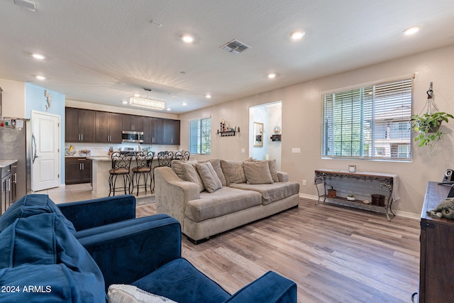 living area featuring recessed lighting, baseboards, visible vents, and light wood-style floors