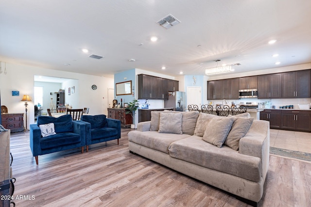 living room featuring recessed lighting, light wood finished floors, and visible vents