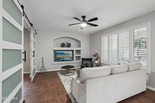 tiled living room featuring a barn door and ceiling fan