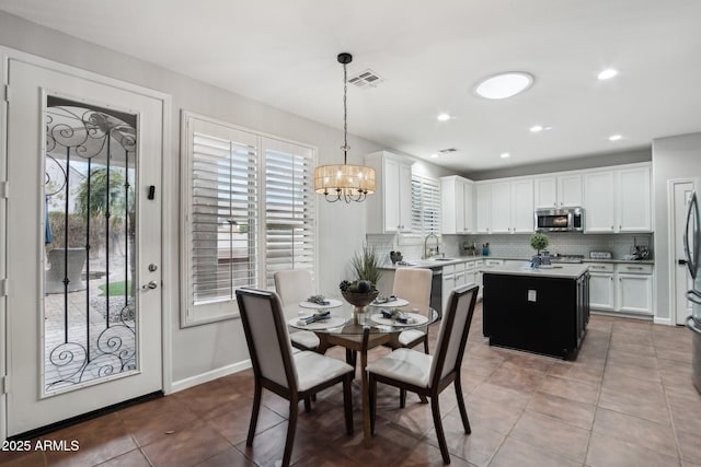 tiled dining space with sink and a notable chandelier