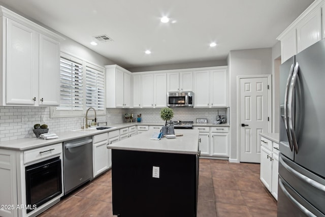 kitchen featuring sink, appliances with stainless steel finishes, a center island, white cabinets, and decorative backsplash