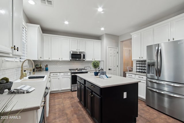 kitchen with a kitchen island, white cabinetry, sink, decorative backsplash, and stainless steel appliances