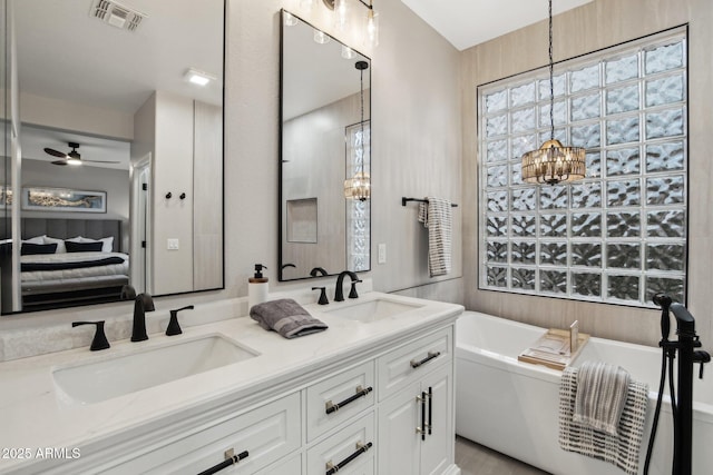 bathroom featuring vanity, ceiling fan with notable chandelier, and a bath