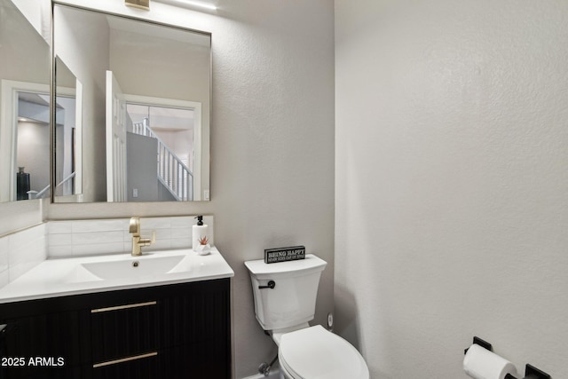 bathroom featuring vanity, toilet, and decorative backsplash