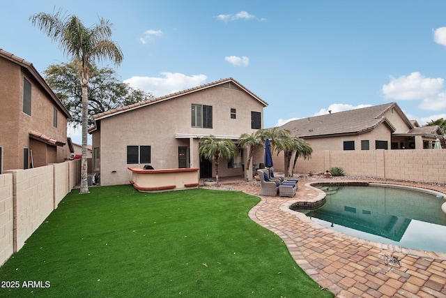 back of house with a pool with hot tub, a patio area, and a lawn