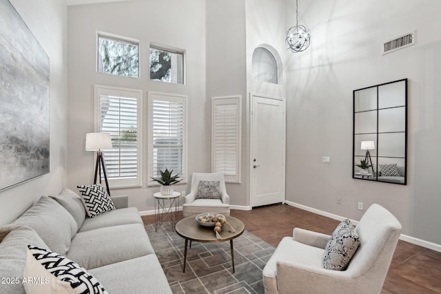 tiled living room with a towering ceiling and a chandelier