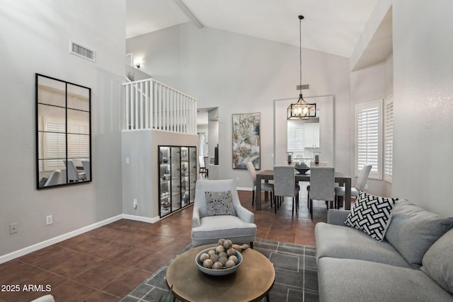 living room with beamed ceiling, dark tile patterned floors, an inviting chandelier, and high vaulted ceiling