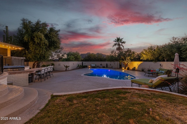 pool at dusk featuring a patio and exterior bar