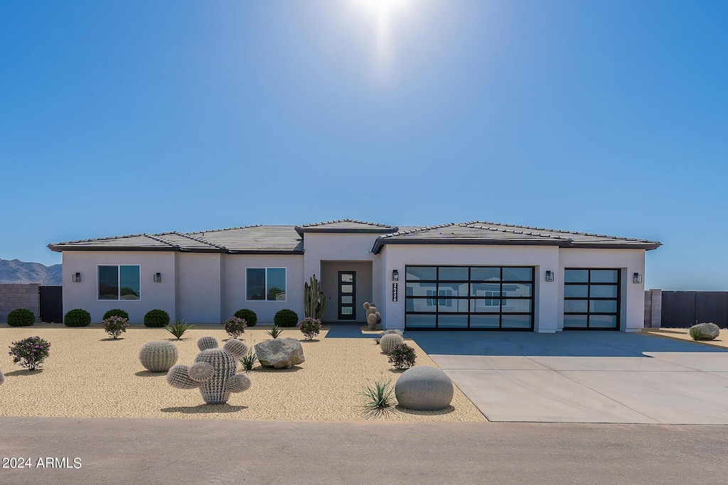 view of front of house with a garage, concrete driveway, a tile roof, and stucco siding